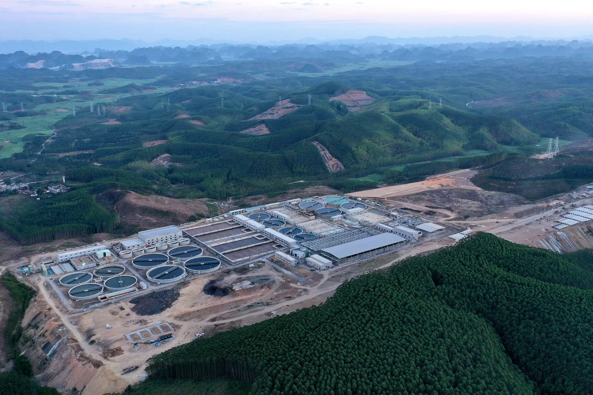 Aerial view of a water treatment and industrial facility surrounded by forested hills and cleared land.