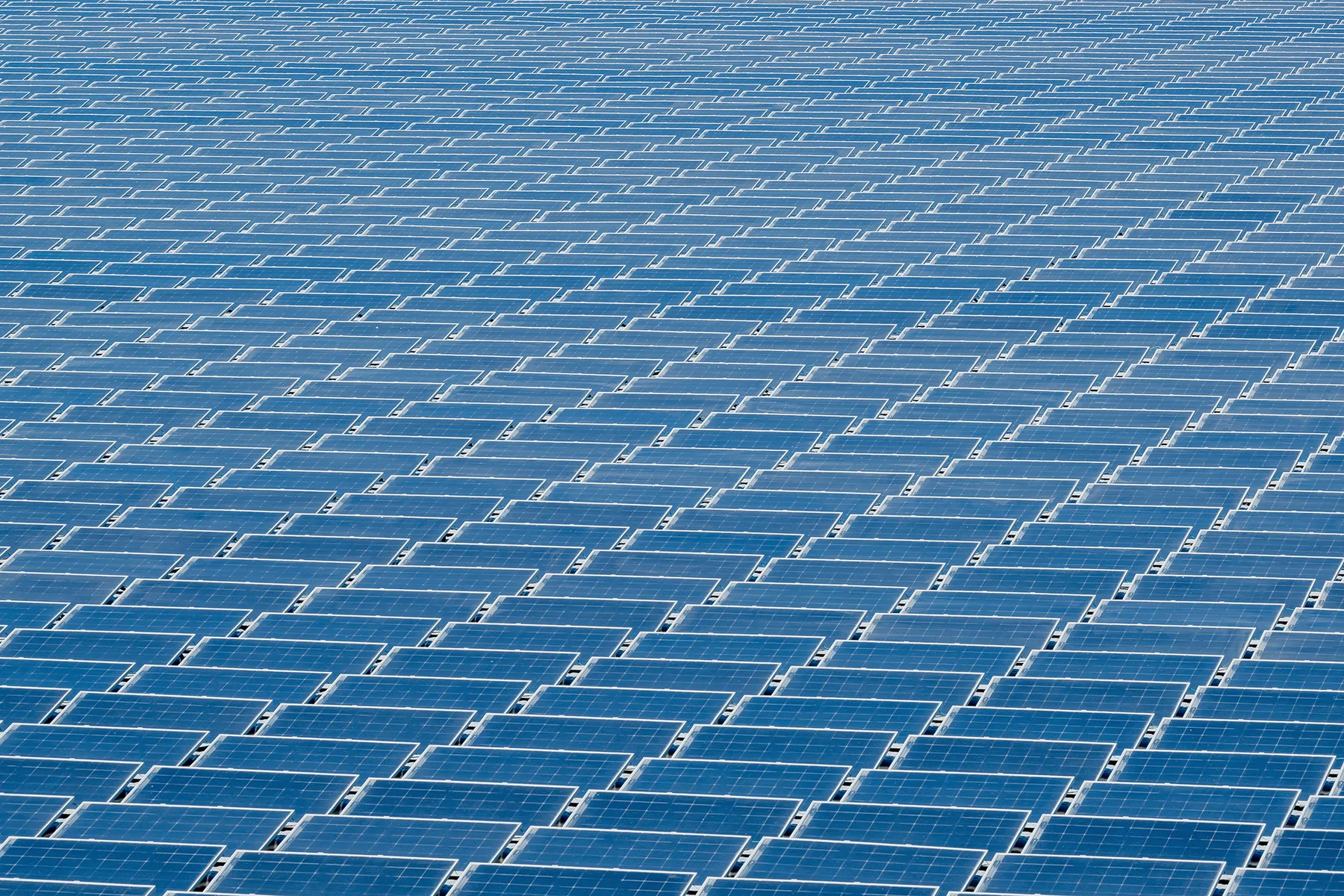 Landscape view across a steel factory site with extensive rows of solar panels covering industrial roofs and adjacent open areas.