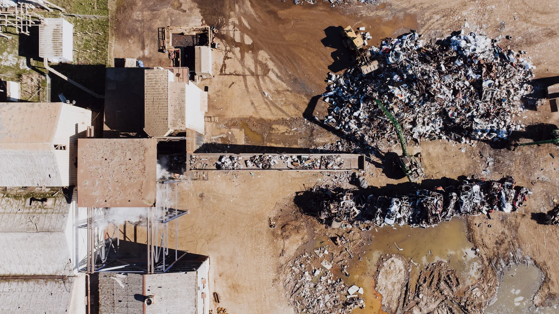 Aerial landscape view of a recycling yard in Chattanooga with separated piles of scrap metal and waste beside access roads and green surroundings.