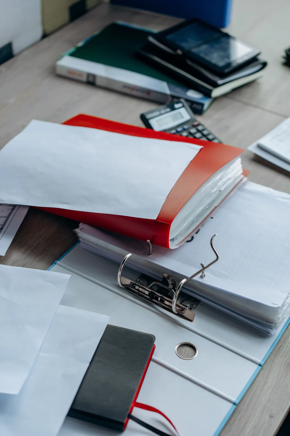 Binders, paperwork and stationery arranged on an office desk.